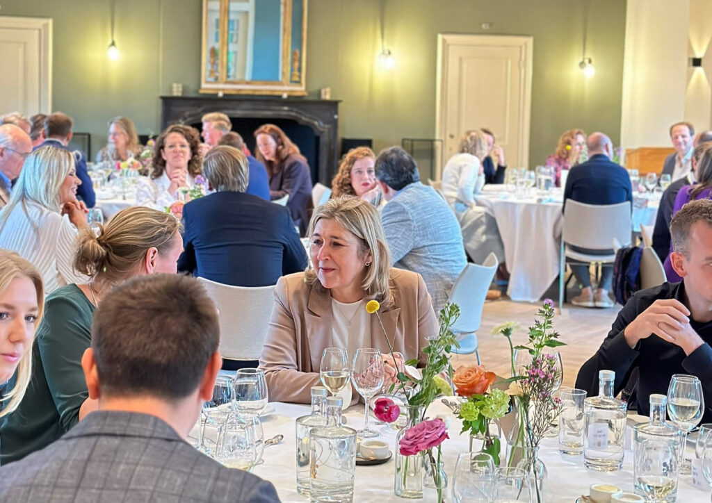 Familieleden zitten gespannen rond een eettafel, als illustratie van ambivalentie in familierelaties, loyaliteit en onderlinge conflicten.